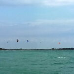 Panoramica dal mare verso l'Isola delle Conchiglie con le vele dei kiter che colorano il mare e il cielo
